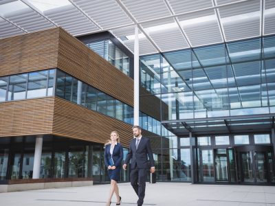 Businessman walking with colleague outside the entrance of an office building